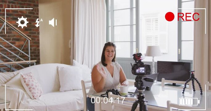Animation of camera screen with digital interface over female vlogger recording vlog at home