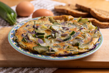 Zucchini and onion omelette served with bread. Complete vegetarian dish.