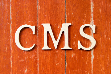 Alphabet letter in word CMS (Abbreviation of Content management system) on old red color wood plate background