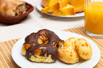 Close up of plate with thread with chocolate icing and cheese bread. Orange juice.