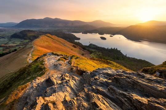 Beautiful golden sunrise over Derwentwater in the Lake District, seen from mountain ridge Catbells on a calm Spring morning.