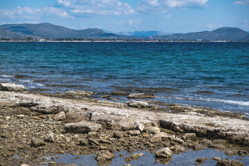 Dry crystal salt on rocky beach. Blue sea background.