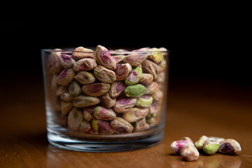 Peeled pistachios in clear glass on wooden table