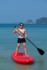 young sporty woman playing stand-up paddle board on the blue sea in sunny day of summer vacation