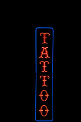 Isolated red and blue neon tattoo sign on black background
