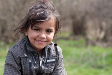 Poster A portrait of smiling beautiful little gypsy girl in a Roma settlement © Konstantyn