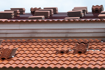 Thick new orange tiles on the roof are placed in order to install the new roof of the building.