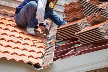 New orange roof tiles, thick plan, are being assembled on the roof by the builders. It is a very dangerous job. By skilled technicians working in Thailand building construction work