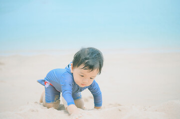 1 year 4 months old baby boy playing sand on the beach,Holidays with baby summer concept.