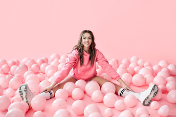 Young trendy woman posing with pink ballons on pink background