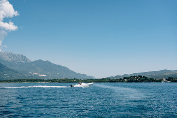 Fototapeta na wymiar Tourists ride on white. sports boat in the sea against the backdrop of mountains in Montenegro. The concept of rich life and travel around the world.
