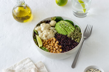 Bowl with avocado, black rice, chickpeas, cabbage, spinach and salad. Healthy eating. Vegetarian food.