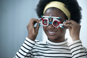 African child girl checking vision with eye test glasses during optic test, optical equipment for examine the vision © chomplearn_2001