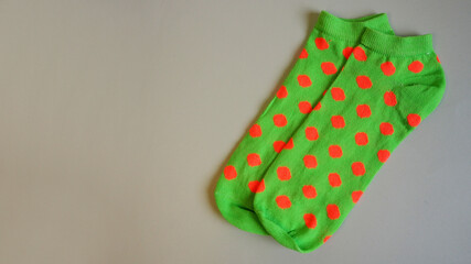 right close short bright green women's socks with orange polka dots lie on a gray background top view