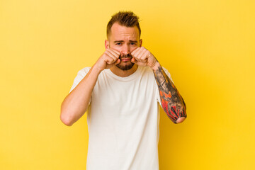 Young tattooed caucasian man isolated on yellow background whining and crying disconsolately.