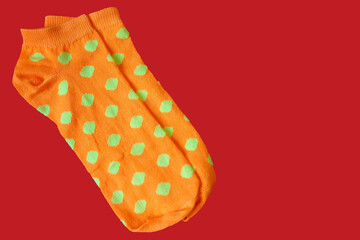 two short bright orange socks with yellow polka dots on a red background top view. women's socks