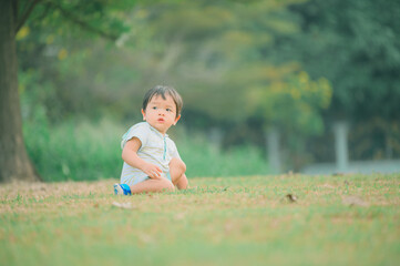 Boy among green grass on a summer day. A small child has fun in the fresh air. Baby explores the nature