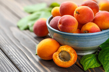 Naklejka na ściany i meble Delicious ripe apricots in a wooden bowl on the table close-up.Healthy fruits. Horizontal top view. Free space for your text.