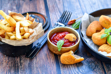 
 Crispy  deep fried     turkey nuggets and ketchup. Breaded  turky efillets  with chilly peppers and fresh basi on wooden rustic background