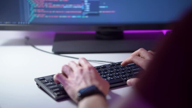 Macro view of mans hands who is typing on keyboard and coding a program on a computer. Work process of a male caucasian person who is writing new html lines. Theme of freelance in field of cyberspace.