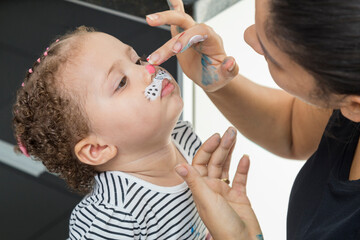 Aunt painting the child's face with her fingers.