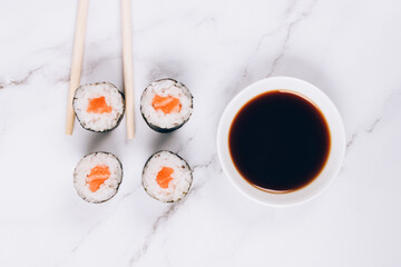 Classic sashimi with salmon fish, soy sauce and chopsticks on white marble table background - maki sushi roll, nori maki, futomaki. Asian food delivery, online home order food concept, sushi bar menu