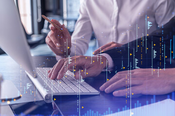 Two traders man and woman researching historic data to predict stock market behavior using laptop. Internet trading concept. Forex and financial hologram chart. Forecasting and planning.