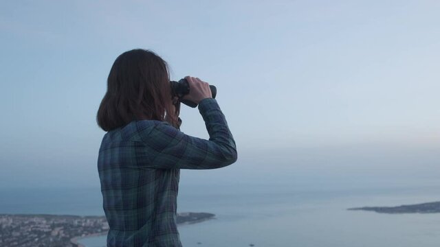 Woman explorer looking into the distance using binoculars.