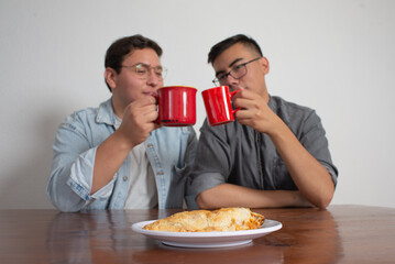 Gay Couple Having Coffee And Sharing A Molote, Mexican Dish