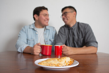Gay Couple Having Coffee And Sharing A Molote, Mexican Dish