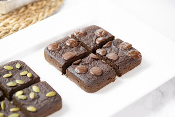 flourless pumpkin chocolate brownies set on white cafe table.