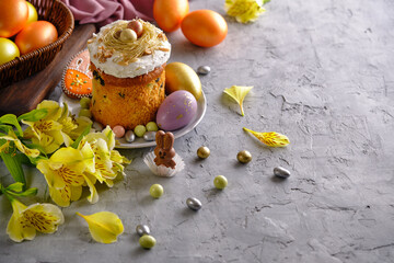 Easter cake with colored eggs and yellow flowers on a gray background
