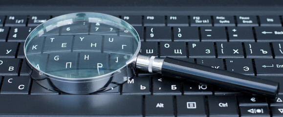 Magnifying Glass On A Black Notebook Keyboard - SEO Concept