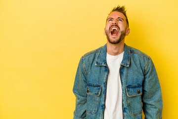 Young tattooed caucasian man isolated on yellow background shouting very angry, rage concept, frustrated.