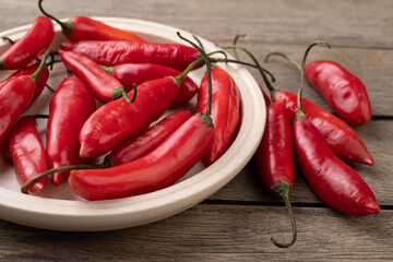 Red chili peppers on a plate over wooden table
