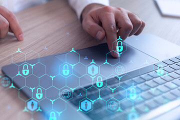 A programmer is typing a code on computer to protect a cyber security from hacker attacks and save clients confidential data. Padlock Hologram icons over the typing hands. Formal wear.
