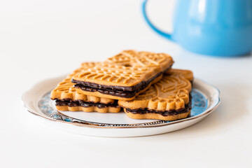 Beautifully illustrated biscuits with dark chocolate on a Herend porcelain plate and a cup of milk.