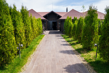 landscape design of a country house. path to the entrance to the house lined with tiles, tui grow along the path. gardener's job.