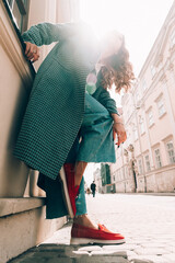 Woman in a red stylish suede loafer shoes, blue jeanse, white shirt and trendy checkered coat...