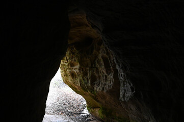 View out of a dark cave, the walls of which are covered with carved symbols.