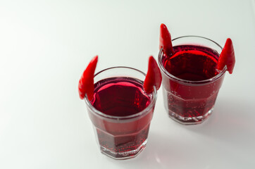 Drink shot prepared with vodka, grenadine and lemon juice decorated with bird eye chillies in the shape of horns