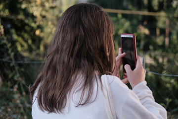 A girl is taking a photo of nature on the smartphone.