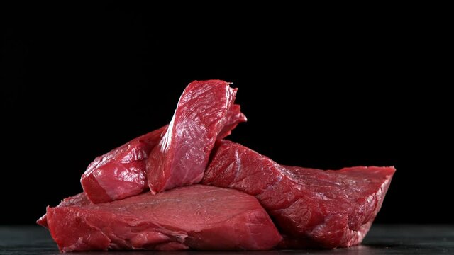 Flying pieces of raw beef steaks falling on table. Filmed on high speed cinema camera, 1000 fps.