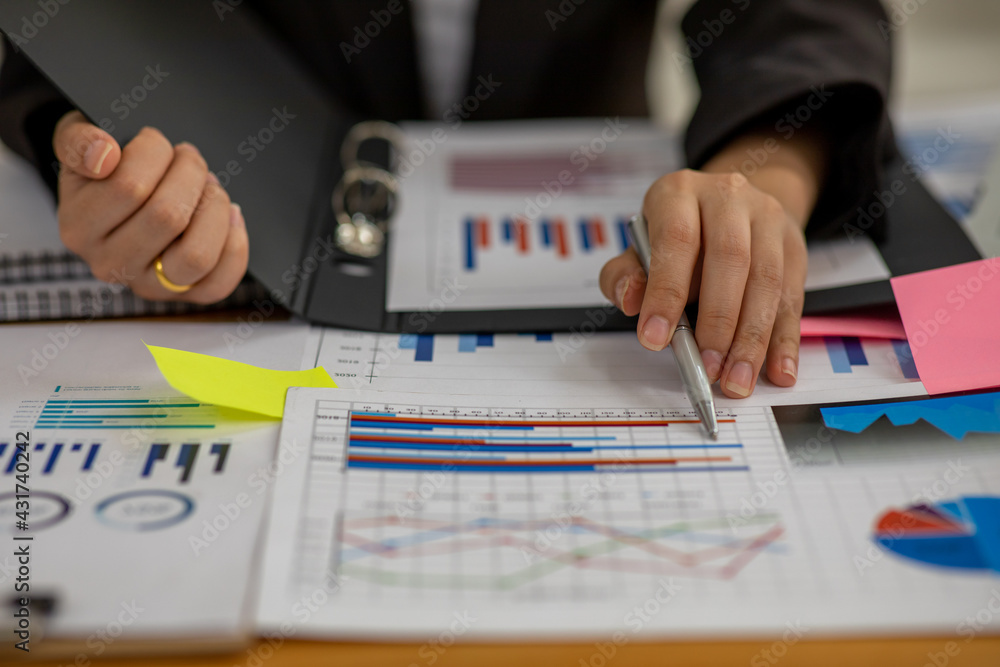 Wall mural Businesswoman hands hold documents with financial statistic stock photo,discussion and analysis data the charts and graphs. Finance concept