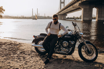 Naklejka premium The biker is resting on the river bank. Evening photo session.