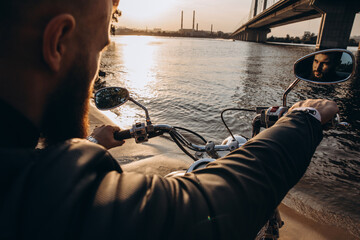 The biker is resting on the river bank. Evening photo session.