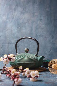 Green japanese cast iron teapot with bamboo whisk and spring blooming twigs