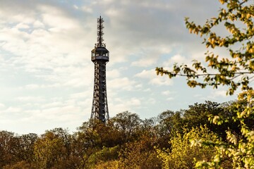 Obraz premium Prague, Czech Republic - May 3 2021: View of the Petrin lookout tower from 1891 standing on a hill surrounded with trees. Spring morning with blue sky and clouds.