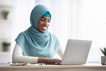 Portrait Of Black Islamic Woman In Hijab Working On Laptop In Office