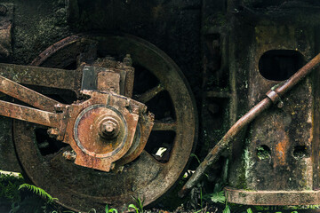 Locomotive wheel made of rusty metal, with a little bit of moss.
